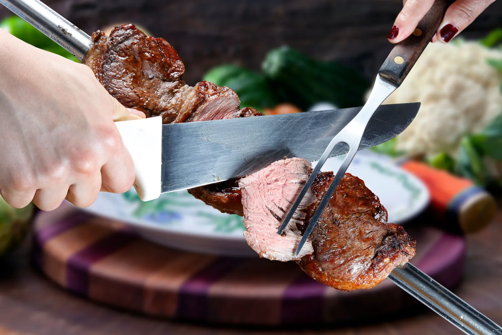 Gaúcho chef carving picanha from the skewer directly onto a guest's plate